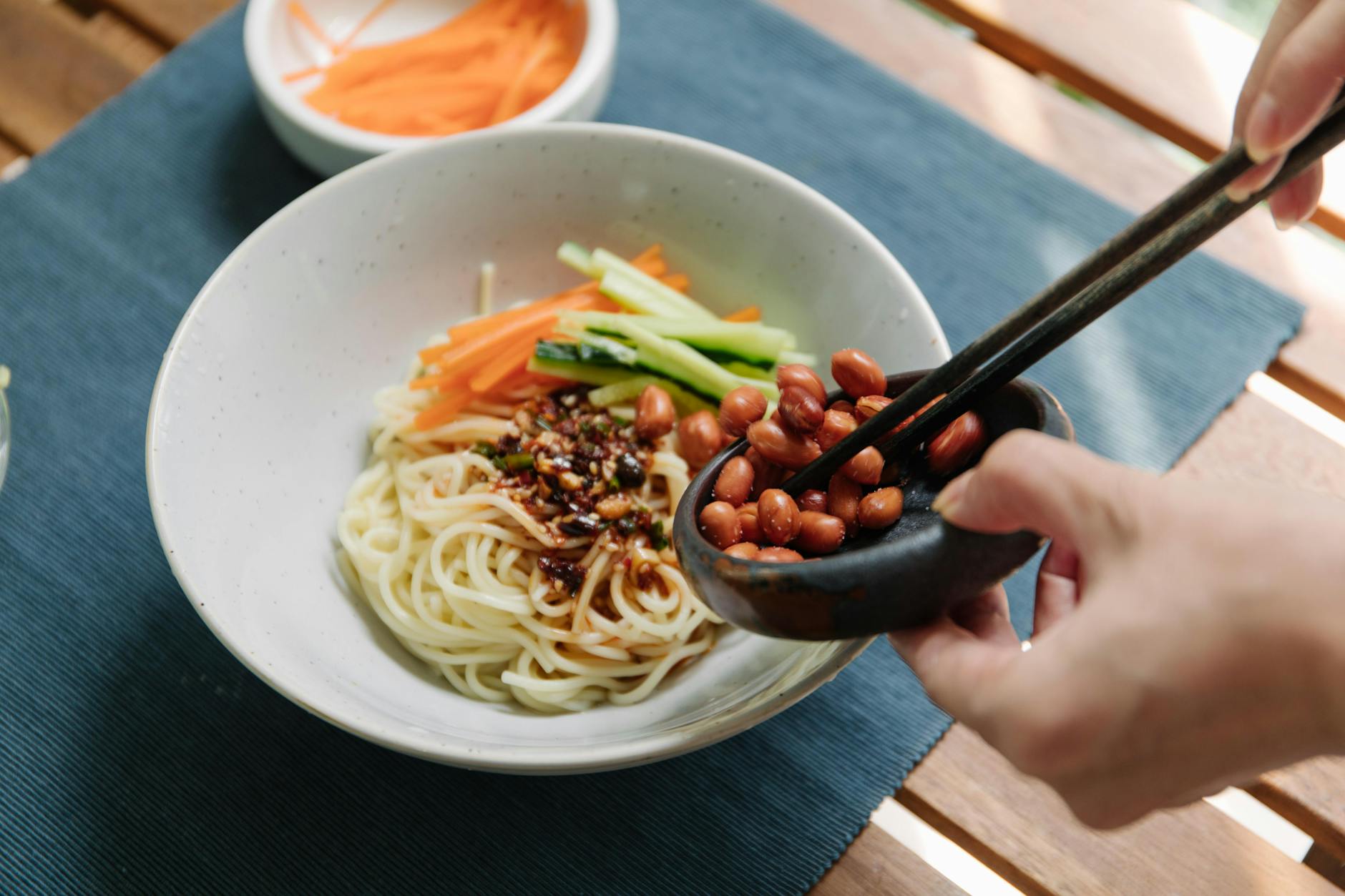 Spicy peanut noodles in a bowl with chopsticks
