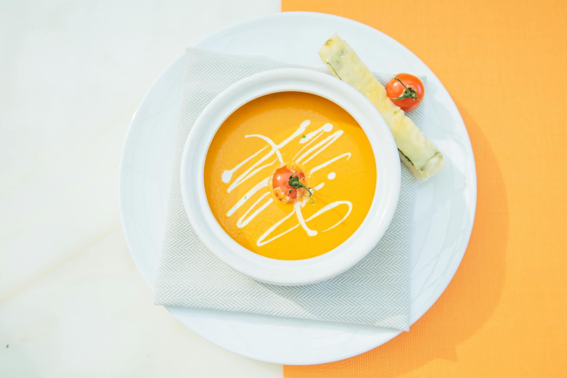 A bowl of creamy tomato soup with a swirl of cream