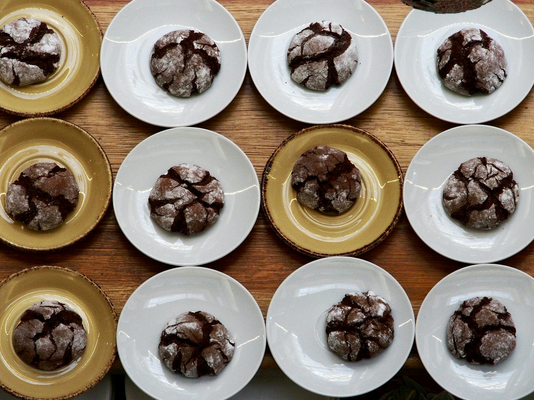 Crinkled brownie cookies with shiny tops on a baking sheet