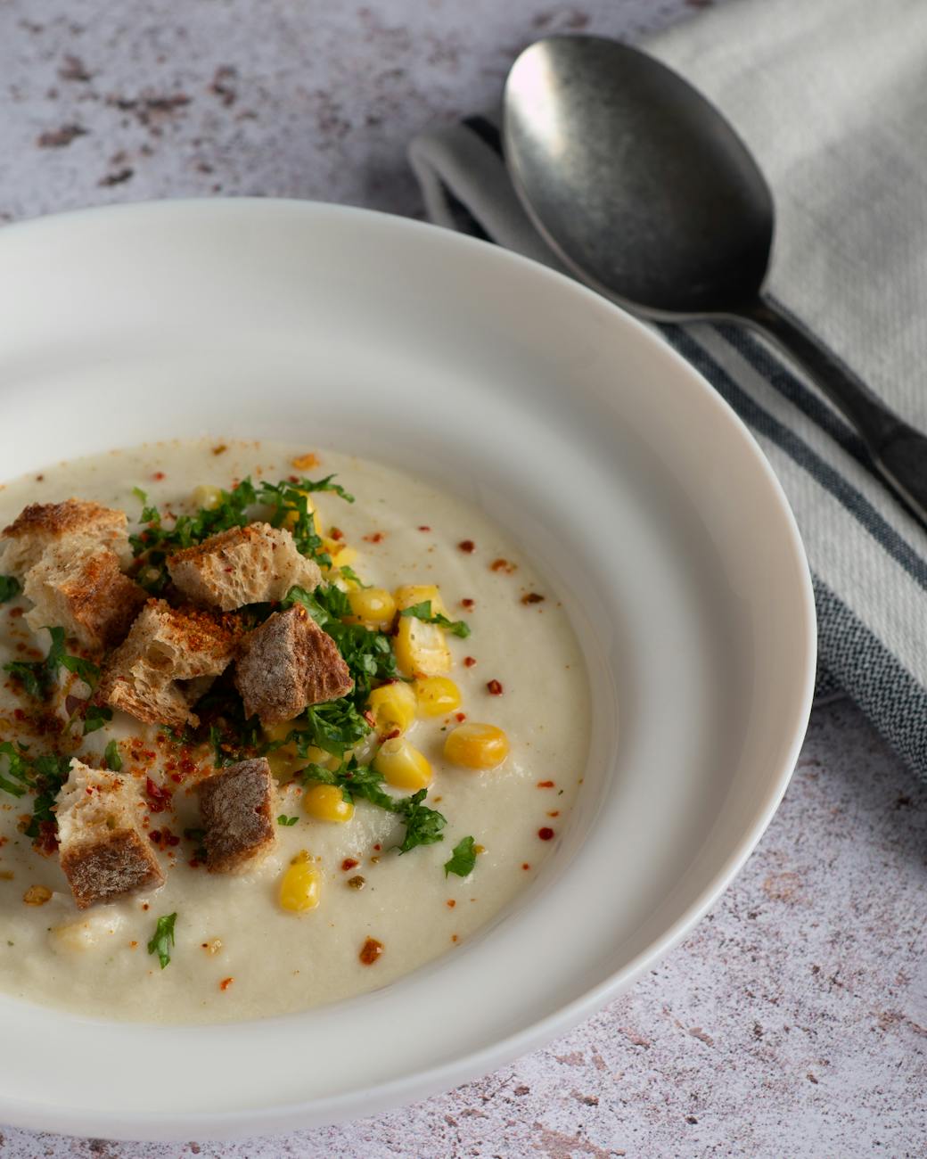 Creamy corn chowder in a bowl with corn kernels and black pepper
