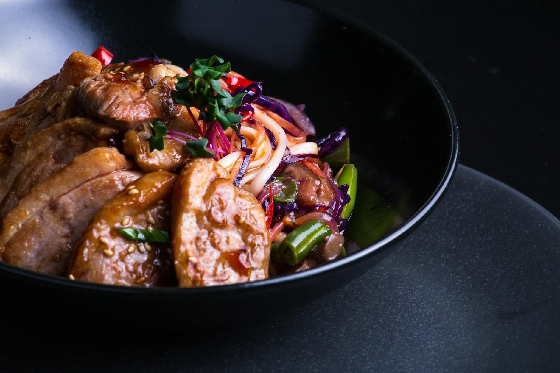 Asian-style stir-fry with ground meat and vegetables in a black bowl
